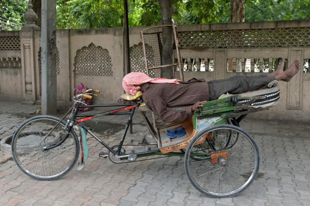 A rickshaw puller takes a nap along a street in Amritsar on April 1, 2026. (Photo by Narinder NANU / AFP)