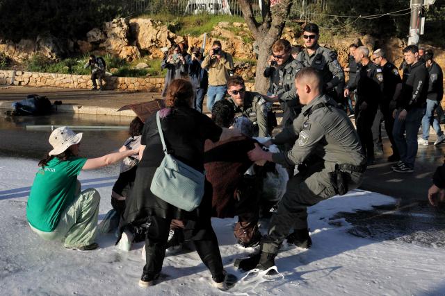 Veteran photographer and former AFP employee Menahem Kahana (top left) lies on the ground next to protesters scuffling with Israeli security forces during a demonstration against a death penalty bill passed by Israel's parliament, outside the parliament in Jerusalem on March 31, 2026. An international media association on March 31, condemned what it described as a "violent and unprovoked attack" on Kahana. According to the Foreign Press Association, which represents hundreds of journalists in Israel and the Palestinian territories, Kahana was "sprayed at a close distance by a water cannon" at the protest outside the Knesset. (Photo by AHMAD GHARABLI / AFP)