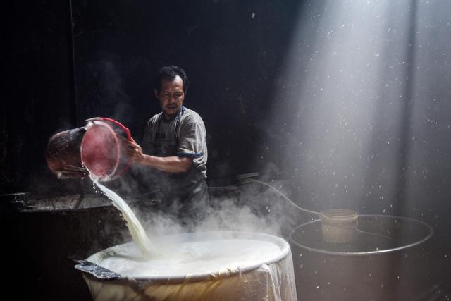 A worker cooks soybean paste to produce traditional tofu in Bandung, West Java, April 1, 2026. (Photo by Timur Matahari / AFP)
