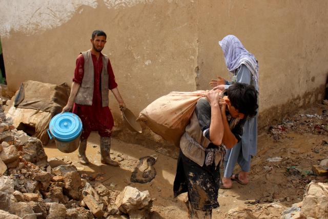Afghan men carry their household goods from damaged homes after flash floods on the outskirts of Pul-e Khumri in Baghlan Province on April 1, 2026. Rain sweeping across Afghanistan has caused floods and landslides in multiple provinces. Among the poorest countries in the world after decades of war, Afghanistan is particularly exposed to the effects of climate change, which scientists say is spurring extreme weather. (Photo by AFP)