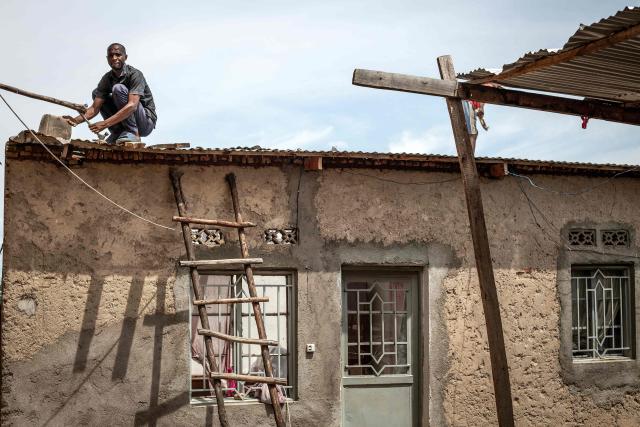 A resident repairs damage caused by shrapnel from munitions that struck the roof of a house following explosions after a fire at a military arsenal in the Musaga district of Bujumbura, on April 1, 2026. Explosions that ripped through the city of Bujumbura after a fire in a military arsenal have killed several dozen people in the Burundian economic capital, security sources told AFP on April 1, 2026.
The explosions erupted late on March 31, 2026 at the main ammunition depot of the Burundi National Defence Force (FDNB) in Musaga, a southern suburb of Bujumbura. (Photo by Fabrice Mbonankira / AFP)