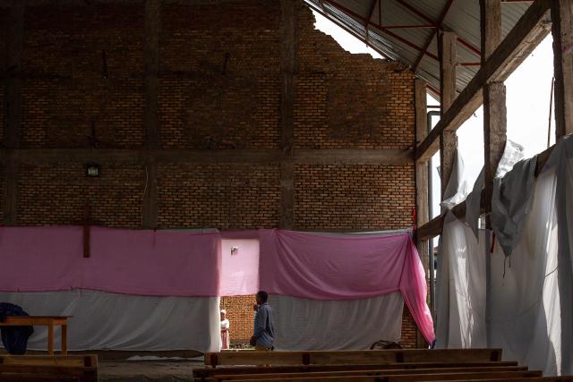 Residents inspect damage caused by shrapnel from munitions that struck the roof of a church following explosions after a fire at a military arsenal in the Musaga district of Bujumbura, on April 1, 2026. Explosions that ripped through the city of Bujumbura after a fire in a military arsenal have killed several dozen people in the Burundian economic capital, security sources told AFP on April 1, 2026.
The explosions erupted late on March 31, 2026 at the main ammunition depot of the Burundi National Defence Force (FDNB) in Musaga, a southern suburb of Bujumbura. (Photo by Fabrice Mbonankira / AFP)