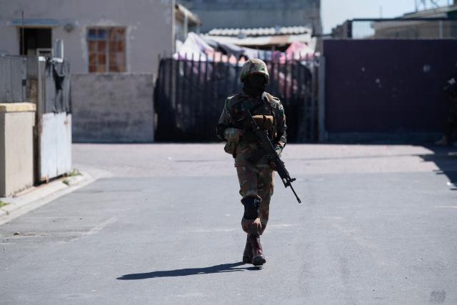 A soldier of the South African National Defence Force (SANDF) walks down a street during a patrol as part of Operation Prosper in Mitchells Plain, near Cape Town, on April 1, 2026. Operation Prosper sees the SANDF play a supporting role to the South African Police Service (SAPS) in crime prevention operations. (Photo by RODGER BOSCH / AFP)