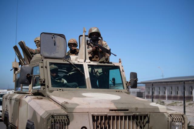 Soldiers of the South African National Defence Force (SANDF) ride in their Mamba armoured vehicle during a patrol as part of Operation Prosper in Mitchells Plain, near Cape Town, on April 1, 2026. Operation Prosper sees the SANDF play a supporting role to the South African Police Service (SAPS) in crime prevention operations. (Photo by RODGER BOSCH / AFP)