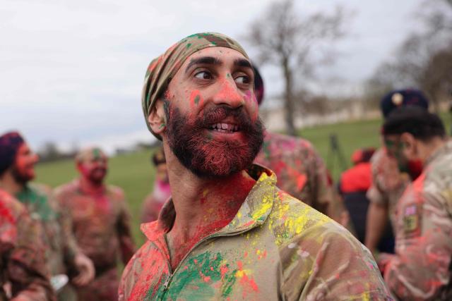 TOPSHOT - Soldiers from the Defence Sikh Network and British Army take part in Rang colour powder throwing during Holla Mohalla, the annual Sikh military festival, celebrating Sikh martial traditions at the Royal Military Academy at Sandhurst on April 01, 2026. Participants took part in a soldier Role fitness test, traditional Sikh martial arts, traditional Sikh military games, and Rang colour powder throwing. The centuries old festival is held in the spirit of fierce but well natured competition and aims to promote courage, preparation, and readiness. Sikhs have been serving in the British Army since the 1800s. (Photo by Adrian DENNIS / AFP)