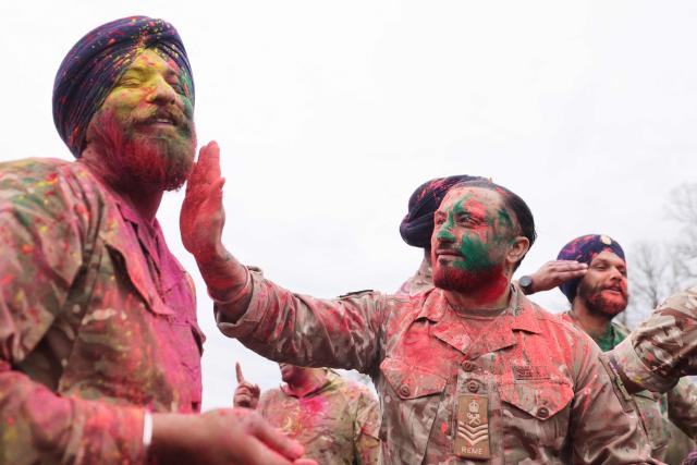 Soldiers from the Defence Sikh Network and British Army take part in Rang colour powder throwing during Holla Mohalla, the annual Sikh military festival, celebrating Sikh martial traditions at the Royal Military Academy at Sandhurst on April 01, 2026. Participants took part in a soldier Role fitness test, traditional Sikh martial arts, traditional Sikh military games, and Rang colour powder throwing. The centuries old festival is held in the spirit of fierce but well natured competition and aims to promote courage, preparation, and readiness. Sikhs have been serving in the British Army since the 1800s. (Photo by Adrian DENNIS / AFP)