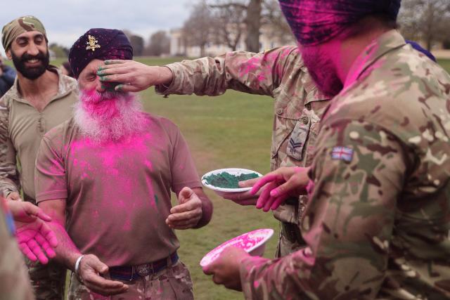 Soldiers from the Defence Sikh Network and British Army take part in Rang colour powder throwing during Holla Mohalla, the annual Sikh military festival, celebrating Sikh martial traditions at the Royal Military Academy at Sandhurst on April 01, 2026. Participants took part in a soldier Role fitness test, traditional Sikh martial arts, traditional Sikh military games, and Rang colour powder throwing. The centuries old festival is held in the spirit of fierce but well natured competition and aims to promote courage, preparation, and readiness. Sikhs have been serving in the British Army since the 1800s. (Photo by Adrian DENNIS / AFP)