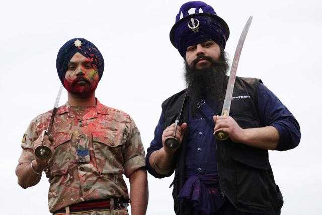 Soldiers from the Defence Sikh Network and British Army take part in Rang colour powder throwing during Holla Mohalla, the annual Sikh military festival, celebrating Sikh martial traditions at the Royal Military Academy at Sandhurst on April 01, 2026. Participants took part in a soldier Role fitness test, traditional Sikh martial arts, traditional Sikh military games, and Rang colour powder throwing. The centuries old festival is held in the spirit of fierce but well natured competition and aims to promote courage, preparation, and readiness. Sikhs have been serving in the British Army since the 1800s. (Photo by Adrian Dennis / AFP)