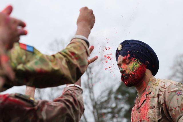 Soldiers from the Defence Sikh Network and British Army take part in Rang colour powder throwing during Holla Mohalla, the annual Sikh military festival, celebrating Sikh martial traditions at the Royal Military Academy at Sandhurst on April 01, 2026. Participants took part in a soldier Role fitness test, traditional Sikh martial arts, traditional Sikh military games, and Rang colour powder throwing. The centuries old festival is held in the spirit of fierce but well natured competition and aims to promote courage, preparation, and readiness. Sikhs have been serving in the British Army since the 1800s. (Photo by Adrian Dennis / AFP)