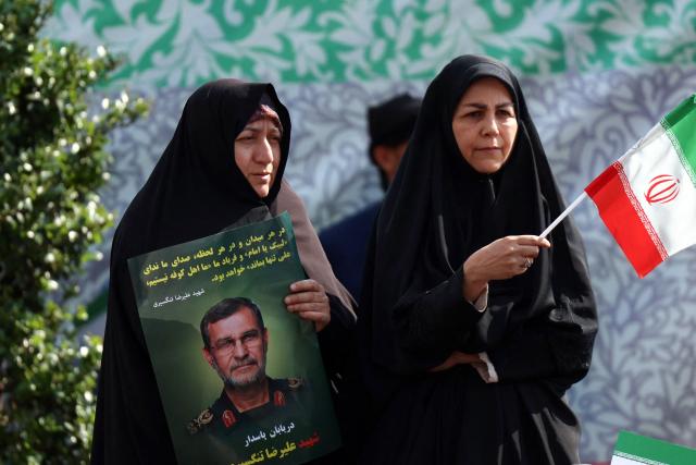 A woman holds a portrait of Alireza Tangsiri, commander of the Iranian Revolutionary Guards' navy during his funeral alongside others killed in US-Israeli strikes on Iran at Enghelab Square in Tehran on April 1, 2026. Iran confirmed on March 30 that an Israeli strike had killed the commander of the naval force of the Revolutionary Guards, who Israel had said was responsible for the blocking of the Strait of Hormuz. A statement carried by the Guards' Sepah News website said Alireza Tangsiri "succumbed to severe injuries" from the attack last week. (Photo by AFP) / 