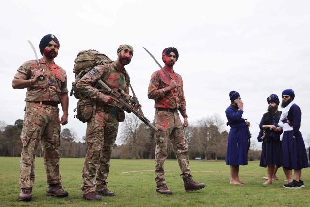 Soldiers from the Defence Sikh Network and British Army take part in Rang colour powder throwing during Holla Mohalla, the annual Sikh military festival, celebrating Sikh martial traditions at the Royal Military Academy at Sandhurst on April 01, 2026. Participants took part in a soldier Role fitness test, traditional Sikh martial arts, traditional Sikh military games, and Rang colour powder throwing. The centuries old festival is held in the spirit of fierce but well natured competition and aims to promote courage, preparation, and readiness. Sikhs have been serving in the British Army since the 1800s. (Photo by Adrian DENNIS / AFP)