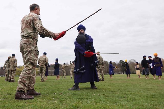 Jathedar Navjeet Singh of the Defence Sikh Network shows Commandant of Sandhurst Major General Nick Crowley of the British Army the science of the weapons as they take part Holla Mohalla, the annual Sikh military festival, celebrating Sikh martial traditions at the Royal Military Academy at Sandhurst on April 01, 2026. Participants took part in a soldier Role fitness test, traditional Sikh martial arts, traditional Sikh military games, and Rang colour powder throwing. The centuries old festival is held in the spirit of fierce but well natured competition and aims to promote courage, preparation, and readiness. Sikhs have been serving in the British Army since the 1800s. (Photo by Adrian DENNIS / AFP)