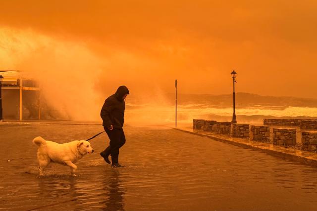 A locql resident walks on the port of Ierapetra during a dust storm on the Greek island of Crete on April 1, 2026. (Photo by Eleftherios Elis / AFP)