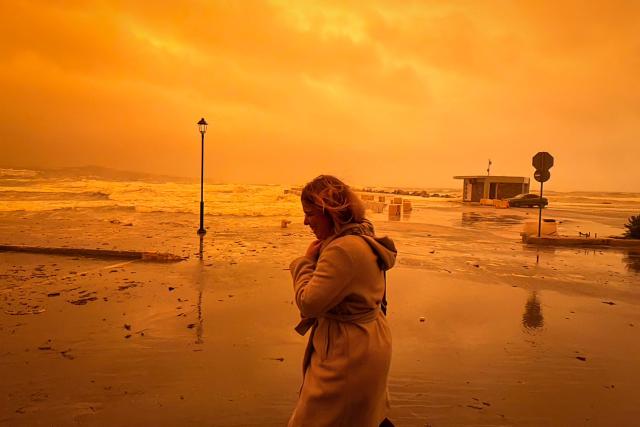 A locql resident walks on the port of Ierapetra during a dust storm on the Greek island of Crete on April 1, 2026. (Photo by Eleftherios Elis / AFP)