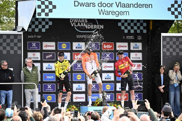 (From L) Silver medallist Team Visma-Lease a Bike's Belgian rider Wout van Aert, gold medallist INEOS Grenadiers' Italian rider Filippo Ganna and bronze medallist Norwegian rider Soren Waerenskjold celebrate on the podium after competing in the men's elite race of the Dwars door Vlaanderen cycling event, 184.6km from Roeselare to Waregem on April 1, 2026. (Photo by JASPER JACOBS / BELGA / AFP) / Belgium OUT