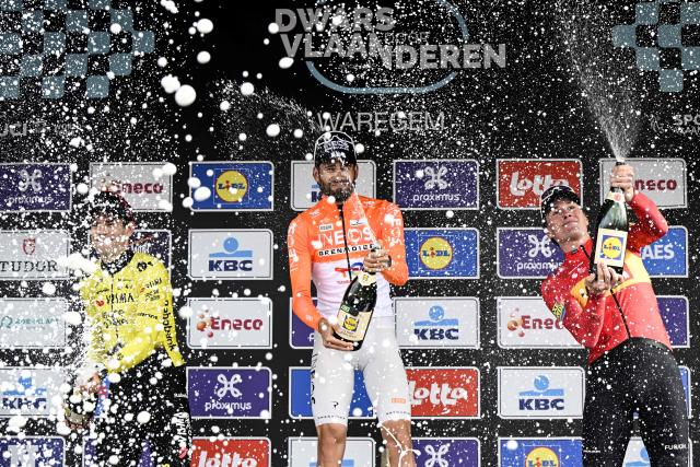 (From L) Silver medallist Team Visma-Lease a Bike's Belgian rider Wout van Aert, gold medallist INEOS Grenadiers' Italian rider Filippo Ganna and bronze medallist Norwegian rider Soren Waerenskjold celebrate on the podium after competing in the men's elite race of the Dwars door Vlaanderen cycling event, 184.6km from Roeselare to Waregem on April 1, 2026. (Photo by Tom Goyvaerts / BELGA / AFP) / Belgium OUT