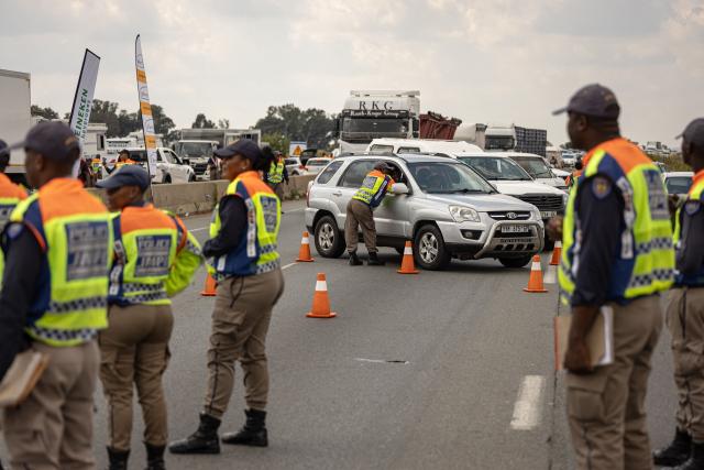 A Johannesburg Metro Police Department (JMPD) officer questions a driver during a roadblock near Johannesburg on April 1, 2026. (Photo by EMMANUEL CROSET / AFP)