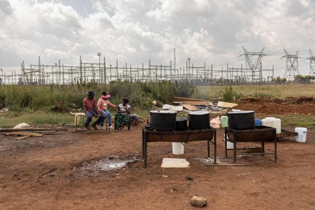 Street vendors talk as they wait for clients in Randfontein on April 1, 2026. (Photo by EMMANUEL CROSET / AFP)