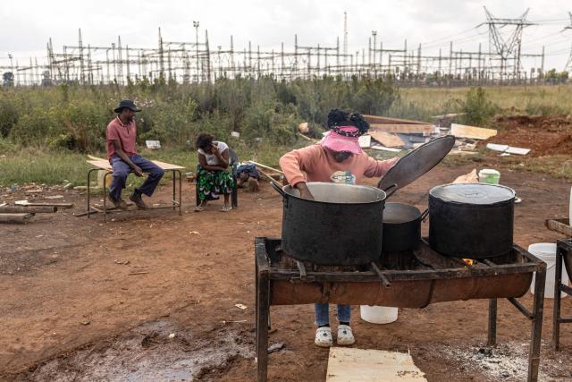 A street vendor stirs a pot of stew as she waits for clients in Randfontein on April 1, 2026. (Photo by EMMANUEL CROSET / AFP)