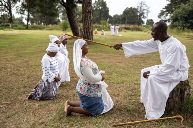 A religious leader positions a stick on a congregant’s head during an open-air service held by the Johani Masowe of Baba Emmanuel church near Randfontein on April 1, 2026. (Photo by EMMANUEL CROSET / AFP)