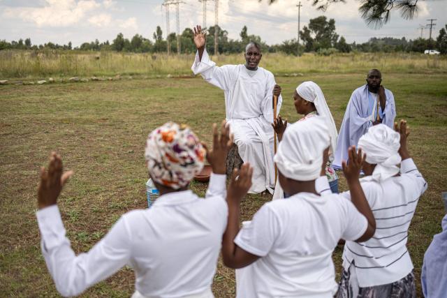 A religious leader preaches as congregants gesture during an open-air service held by the Johani Masowe of Baba Emmanuel church near Randfontein on April 1, 2026. (Photo by EMMANUEL CROSET / AFP)