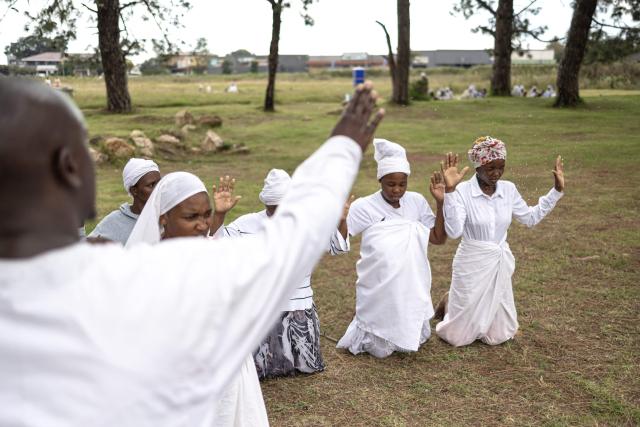 A religious leader throws water at congregants during an open-air service held by the Johani Masowe of Baba Emmanuel church near Randfontein on April 1, 2026. (Photo by EMMANUEL CROSET / AFP)