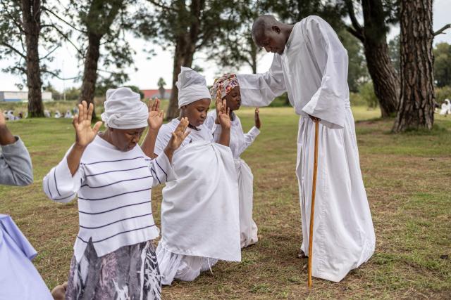 A religious leader prays for congregants during an open-air service held by the Johani Masowe of Baba Emmanuel church near Randfontein on April 1, 2026. (Photo by EMMANUEL CROSET / AFP)