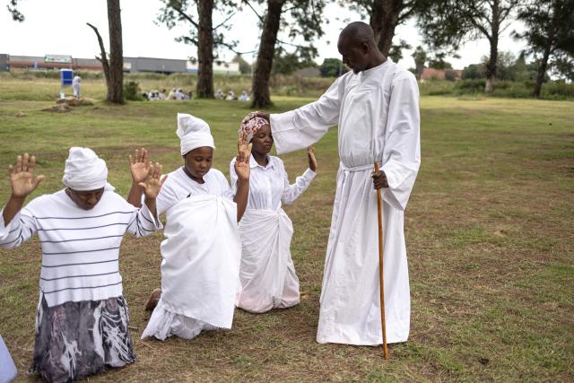 A religious leader prays for congregants during an open-air service held by the Johani Masowe of Baba Emmanuel church near Randfontein on April 1, 2026. (Photo by EMMANUEL CROSET / AFP)