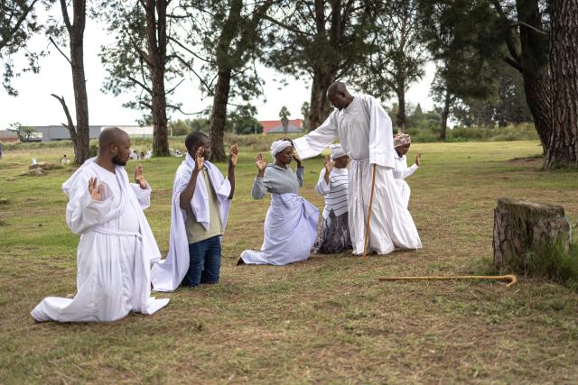 A religious leader prays for congregants during an open-air service held by the Johani Masowe of Baba Emmanuel church near Randfontein on April 1, 2026. (Photo by EMMANUEL CROSET / AFP)