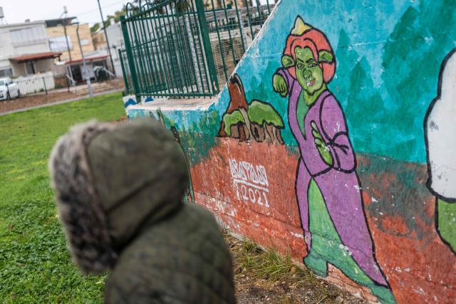 A woman stands outside a shelter as she waits for warning sirens in Akko (Acre), northern Israel on April 1, 2026. The Israeli military said its air defences responded to a missile attack from Iran on April 1, with warning sirens activated across central Israel. (Photo by Ilia YEFIMOVICH / AFP) / 