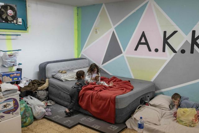 Israeli children look at mobile phones while inside a shelter following warning sirens in Akko (Acre), northern Israel on April 1, 2026. The Israeli military said its air defences responded to a missile attack from Iran on April 1, with warning sirens activated across central Israel. (Photo by Ilia YEFIMOVICH / AFP) / 