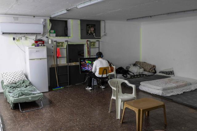 An Israeli teenager plays video games in the shelter following warning sirens in Akko (Acre), northern Israel on April 1, 2026. The Israeli military said its air defences responded to a missile attack from Iran on April 1, with warning sirens activated across central Israel. (Photo by Ilia YEFIMOVICH / AFP) / 