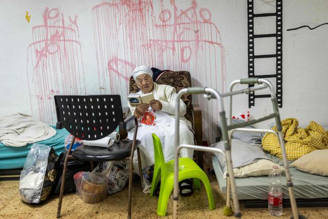 A religious woman reads inside a shelter ahead of Passover celebration in Akko (Acre), northern Israel on April 1, 2026. According to biblical narrative, due to the haste with which the Jews left Egypt, the bread they had prepared for the journey did not have time to rise. To commemorate their ancestors' plight, the religious avoid eating leavened food products throughout Passover. (Photo by Ilia YEFIMOVICH / AFP)