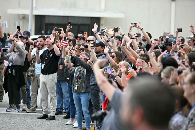Loved ones and colleaugues wave to the Artemis II mission crew as they walk out before traveling to the launch pad to board the Space Launch System (SLS) rocket for the Artemis II crewed lunar mission at Kennedy Space Center in Cape Canaveral, Florida, on April 1, 2026. On Wednesday three men and one woman are set to embark on the first crewed journey to the Moon since 1972, a landmark odyssey that aims to launch the US into a new era of space exploration. The NASA mission dubbed Artemis 2 has been years in the making after facing repeated setbacks, but is finally scheduled to take off from Florida as early as April 1 at 6:24 pm (2224 GMT). (Photo by Jim WATSON / AFP)