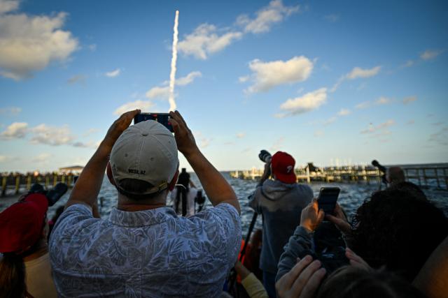 Space enthusiasts at a park in Titusville, view the Artemis II crewed lunar mission lift off from Pad 39B at Kennedy Space Center in Cape Canaveral, Florida, on April 1, 2026. Four astronauts blasted off aboard a massive NASA rocket April 1 on a long-anticipated journey around the Moon, the first crewed lunar flyby in more than 50 years. With an intense roar that reverberated far beyond the launchpad, the enormous orange-and-white rocket carried three Americans and one Canadian away from Florida's Kennedy Space Center at approximately 6:35 pm local time, according to an AFP journalist onsite. "We're going to the Moon!" yelled a spectator. (Photo by Miguel J Rodriguez Carrillo / AFP)