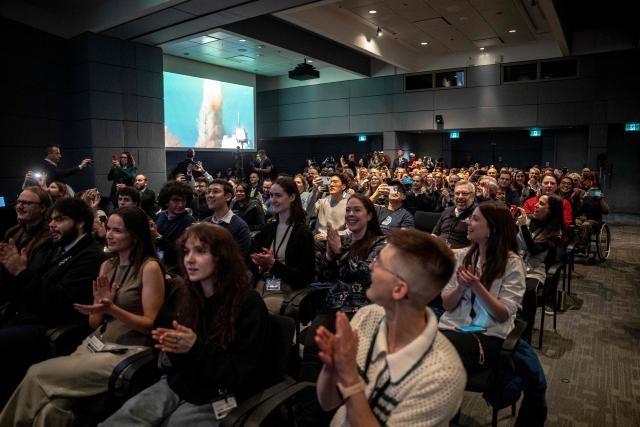 People react while watching the live broadcast of the Artemis II lunar mission launch, with Canadian Space Agency (CSA) astronaut Jeremy Hansen on board, during a viewing party at the CSA offices in Longueuil, near Montreal, Quebec, on April 1, 2026. Four astronauts blasted off aboard a massive NASA rocket April 1 on a long-anticipated journey around the Moon, the first crewed lunar flyby in more than 50 years. With an intense roar that reverberated far beyond the launchpad, the enormous orange-and-white rocket carried three Americans and one Canadian away from Florida's Kennedy Space Center at approximately 6:35 pm local time, according to an AFP journalist onsite. "We're going to the Moon!" yelled a spectator. (Photo by ANDREJ IVANOV / AFP)
