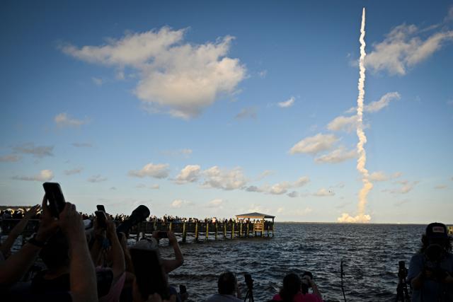 Space enthusiasts at a park in Titusville, view the Artemis II crewed lunar mission lift off from Pad 39B at Kennedy Space Center in Cape Canaveral, Florida, on April 1, 2026. Four astronauts blasted off aboard a massive NASA rocket April 1 on a long-anticipated journey around the Moon, the first crewed lunar flyby in more than 50 years. With an intense roar that reverberated far beyond the launchpad, the enormous orange-and-white rocket carried three Americans and one Canadian away from Florida's Kennedy Space Center at approximately 6:35 pm local time, according to an AFP journalist onsite. "We're going to the Moon!" yelled a spectator. (Photo by Miguel J Rodriguez Carrillo / AFP)