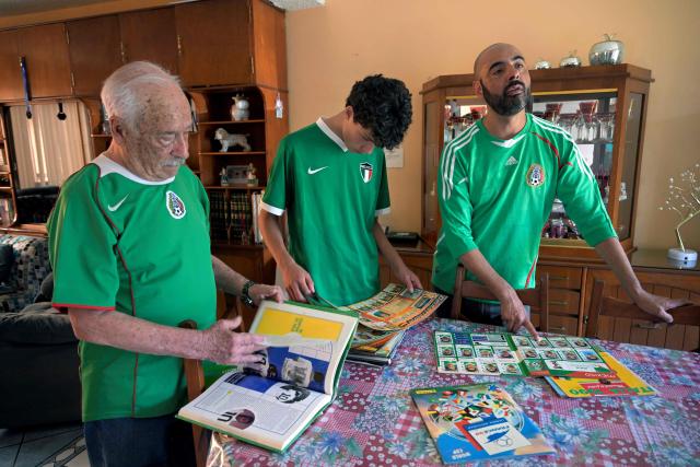 Fernando Rueda, Emilio Rueda, and Victor Hugo Rueda alias "Jairo" review their football albums from previous World Cups during an interview with AFP in Mexico City on March 21, 2026. The Ruedas, Fernando, Jairo and Emilio, are three generations of Mexicans who can no longer afford a World Cup ticket due to the surge in prices compared with the two previous tournaments hosted in the country. (Photo by Alfredo ESTRELLA / AFP)