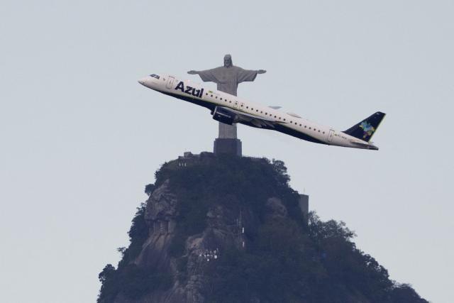 (FILES) An Azul Brazilian Airlines plane flies past the Christ the Redeemer statue after taking off from Rio de Janeiro’s Santos Dumont Airport, on October 5, 2025, as seen from Niteroi, Brazil. Brazilian airlines warned on April 1, 2026, that the more than 50% increase in fuel prices due to the impact of the war in the Middle East will have “severe consequences” for the availability of air travel in the country. (Photo by Pablo PORCIUNCULA / AFP)