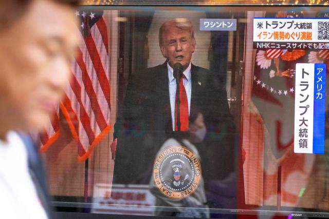 A passerby walks past a television screen showing a live broadcast of US President Donald Trump delivering national address on war against Iran, along a street in Tokyo on April 2, 2026. (Photo by Kazuhiro NOGI / AFP)