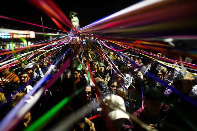 Catholic faithful hold colored tape tied to a statue of Jesus Christ as they take part in a procession known as "Jesus Nazareno of the tapes," during the Holy Week in Cartago, Costa Rica on April 1, 2026. (Photo by Ezequiel BECERRA / AFP)