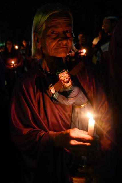 A woman holds a candle as she takes part in a procession by Catholic faithful and relatives of political prisoners outside El Rodeo prison during Holy Week in Guatire, Miranda state, Venezuela on April 1, 2026. (Photo by Maryorin Mendez / AFP)