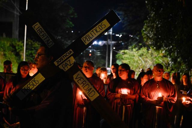 A man carries a cross as he takes part in a procession by Catholic faithful and relatives of political prisoners outside El Rodeo prison during Holy Week in Guatire, Miranda state, Venezuela on April 1, 2026. (Photo by Maryorin Mendez / AFP)