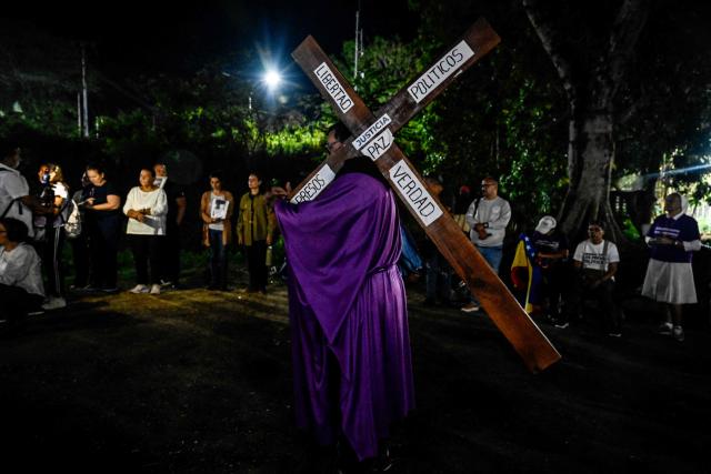 A man carries a cross as he takes part in a procession by Catholic faithful and relatives of political prisoners outside El Rodeo prison during Holy Week in Guatire, Miranda state, Venezuela on April 1, 2026. (Photo by Maryorin Mendez / AFP)