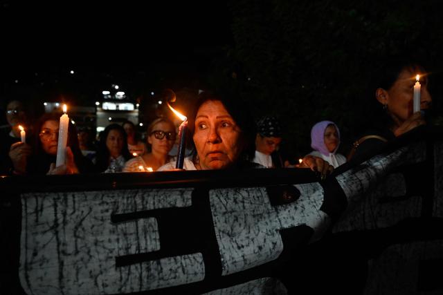 A woman holds a candle as she takes part in a procession by Catholic faithful and relatives of political prisoners outside El Rodeo prison during Holy Week in Guatire, Miranda state, Venezuela on April 1, 2026. (Photo by Maryorin Mendez / AFP)