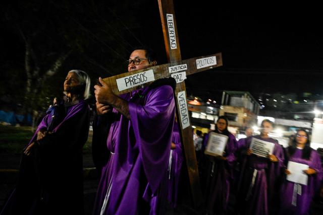 A man carries a cross as he takes part in a procession by Catholic faithful and relatives of political prisoners outside El Rodeo prison during Holy Week in Guatire, Miranda state, Venezuela on April 1, 2026. (Photo by Maryorin Mendez / AFP)