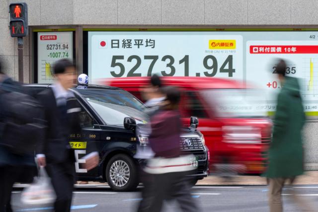 An electronic quotation boards displays the Nikkei Stock Average on the Tokyo Stock Exchange (top) along a street in Tokyo on April 2, 2026. (Photo by Kazuhiro NOGI / AFP)