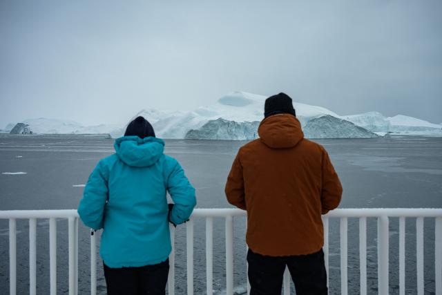 Tourists watch icebergs drift from the deck of the Sarfaq Ittuk ferry in Disko Bay, near Ilulissat, Greenland, on March 15, 2026. The Sarfaq Ittuk is a vital and iconic coastal ferry for Greenlanders, keeping small west coast communities connected to low cost. It links Qaqortoq in the south to Ilulissat in the north in a week-long journey. This year, an unusually warm January allowed the ferry to reach Ilulissat much earlier than usual, as the town is normally blocked by sea ice in March. Around 200 passengers travel on board for medical needs, work, tourism, or simply to meet people. But with new airports opening and a lack of investors, the future of the Sarfaq Ittuk is increasingly uncertain. (Photo by Florent VERGNES / AFP)