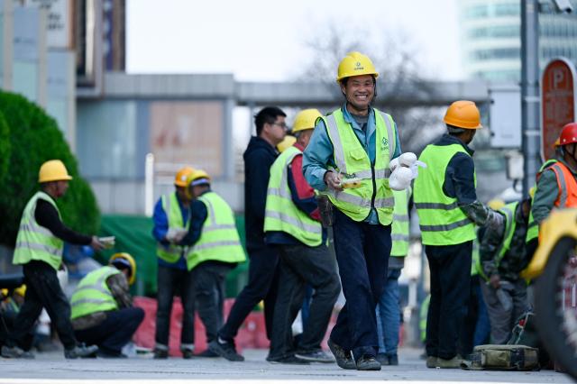 A group of workers spend their lunch time along a road in Beijing on April 2, 2026. (Photo by WANG Zhao / AFP)