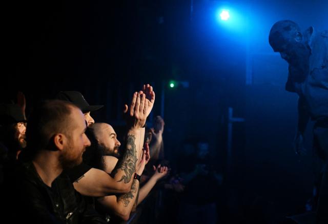 Spectators cheer towards he frontman of the Ukrainian metal band "1914" Dmytro Ternushchak (R), aka "Kumar", as he performs on stage during a concert at the Proxima music club in Warsaw on March 25, 2026. Like other bands, "1914" is raising money for the Ukrainian army. Kumar is attempting to "open the eyes" of Europeans in light of the Kremlin's warmongering, showing that Ukraine poses as an "eastern shield". Their latest album, released in November 2025, follows the story of a Ukrainian from Galicia in their fight against Russia in the First World War. (Photo by Sergei GAPON / AFP)